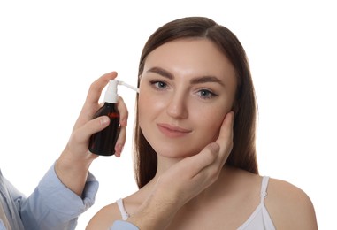 Man spraying medication into woman`s ear on white background