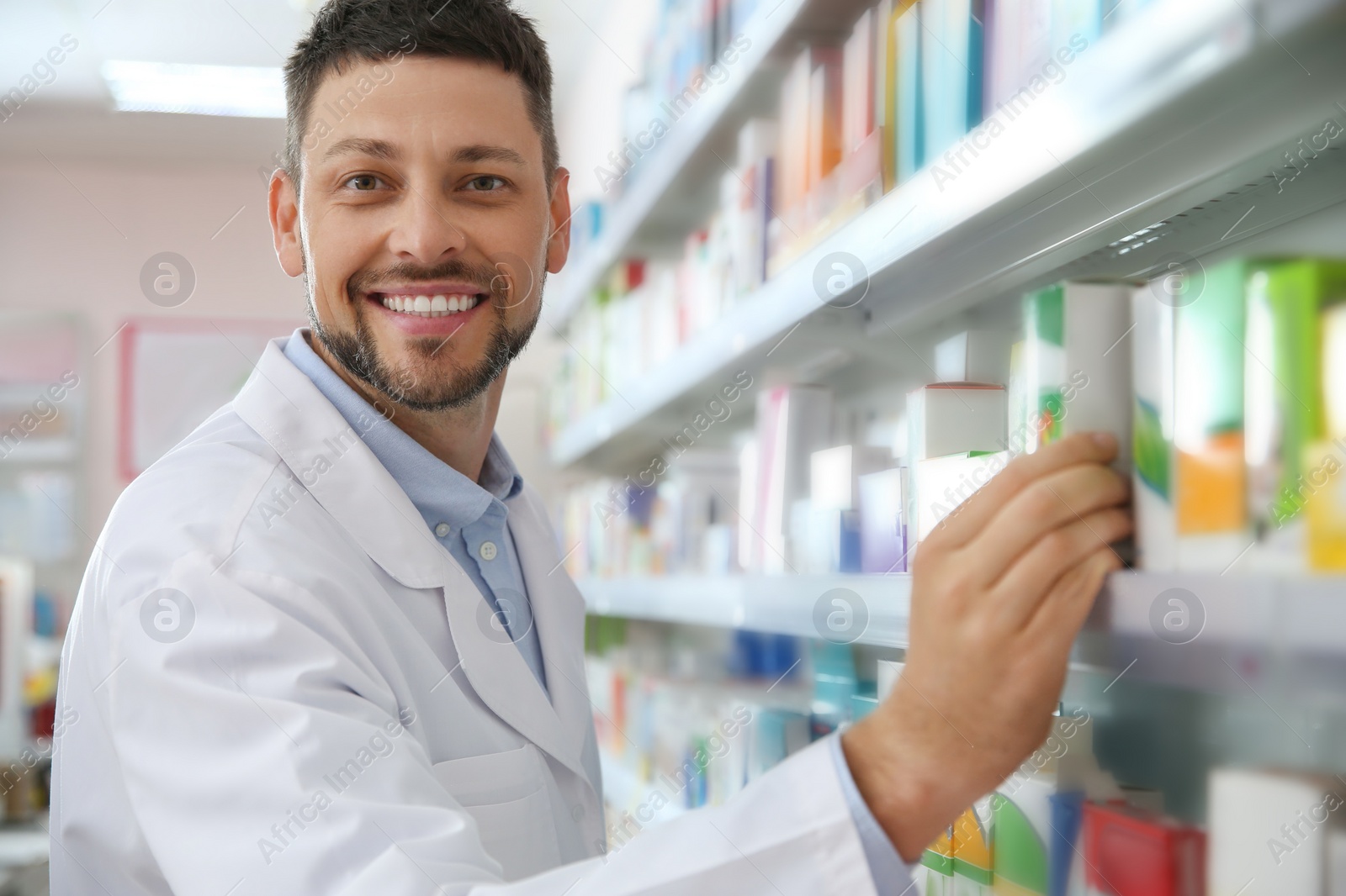Photo of Professional pharmacist near shelves with merchandise in drugstore
