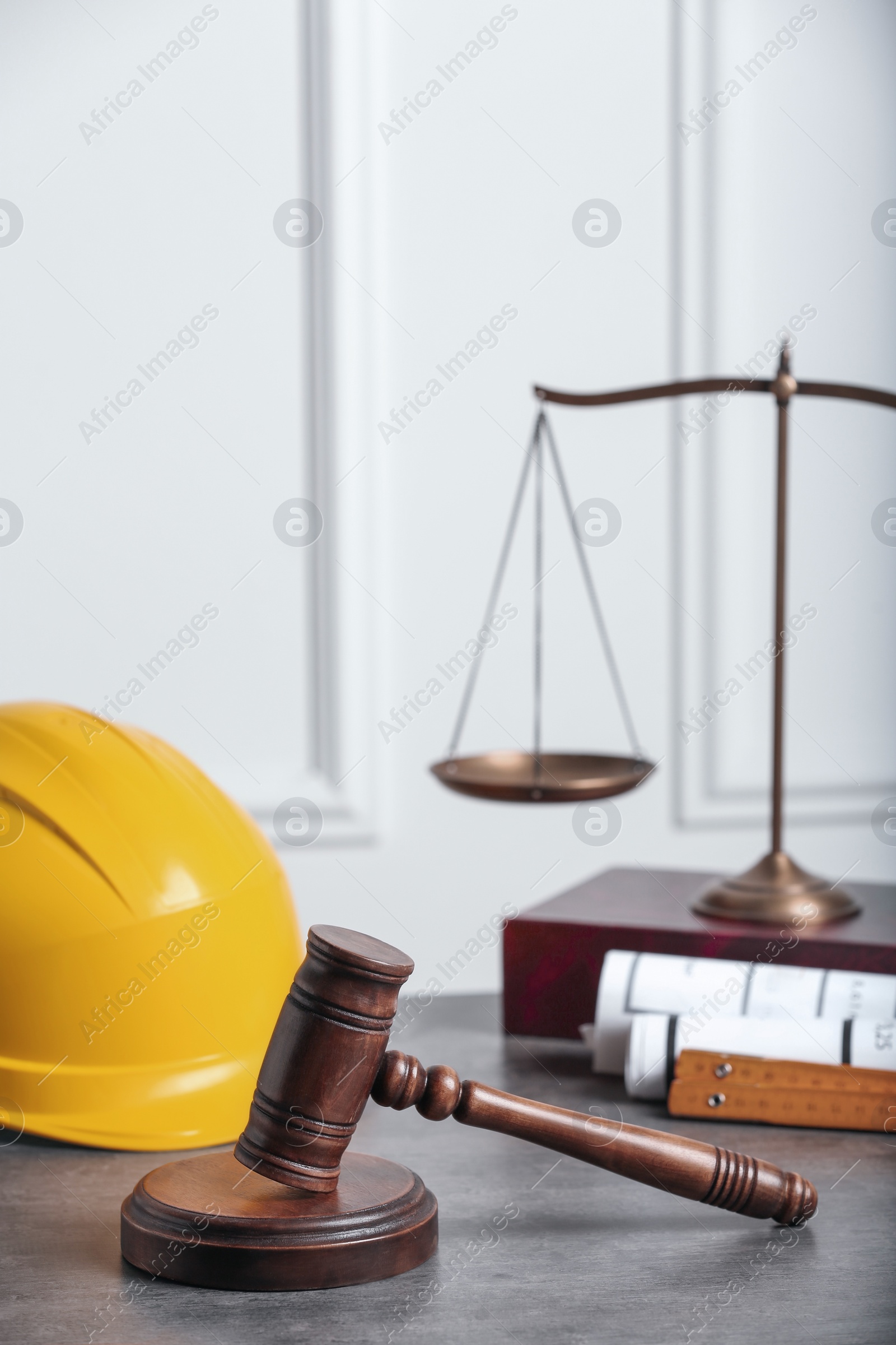 Photo of Construction and land law concepts. Judge gavel, scales of justice, protective helmet with drawings on grey table