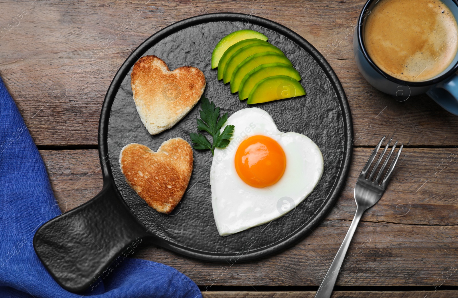 Photo of Romantic breakfast with fried heart shaped egg, avocado and toasts on wooden table, flat lay. Valentine's day celebration