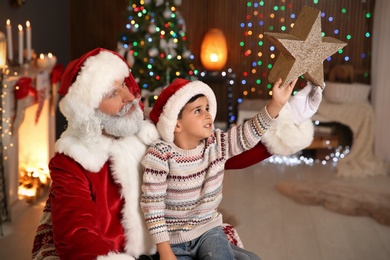 Photo of Little child with Santa Claus and Christmas star at home