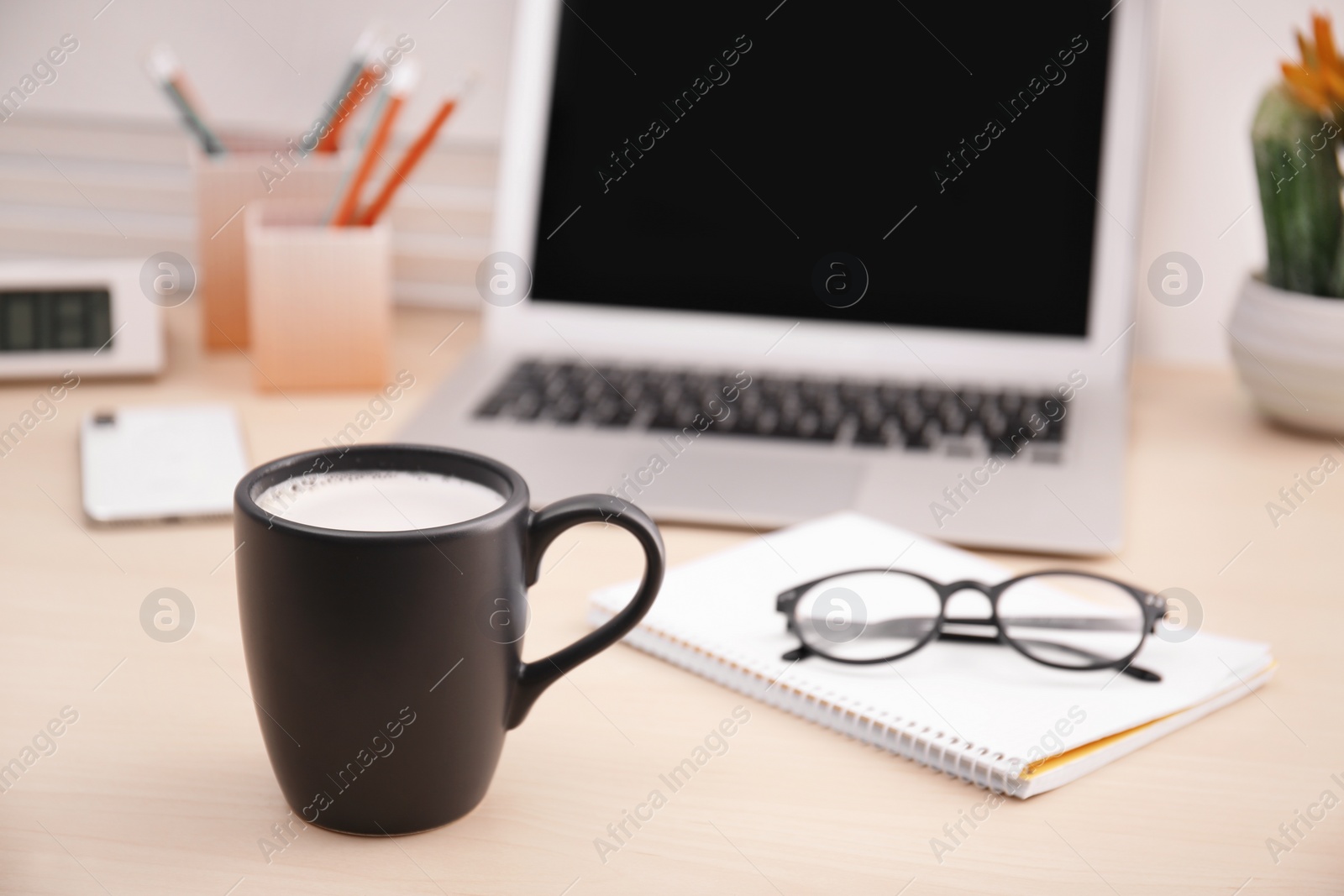 Photo of Black cup with coffee, glasses and notebook on office table. Break time