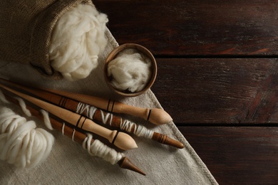 Photo of Soft wool and spindles on white wooden table, flat lay. Space for text