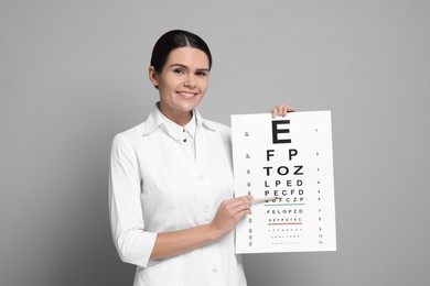Photo of Ophthalmologist pointing at vision test chart on gray background