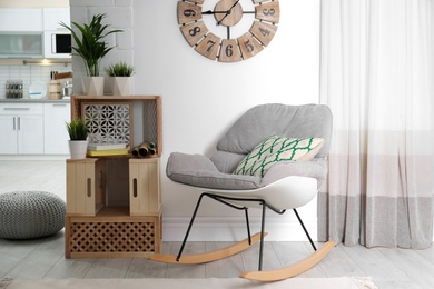 Photo of Rocking chair and wooden crates in room interior. Eco style