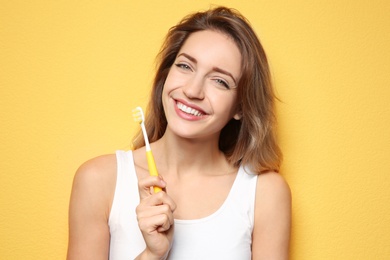 Portrait of young woman with toothbrush on color background