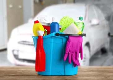 Bucket with cleaning supplies on wooden surface at car wash