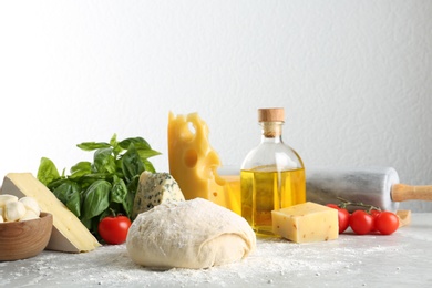 Dough and fresh ingredients for pizza on light table
