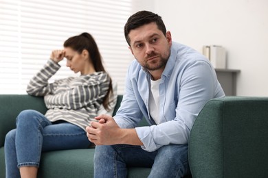 Offended couple ignoring each other after quarrel indoors, selective focus. Relationship problems