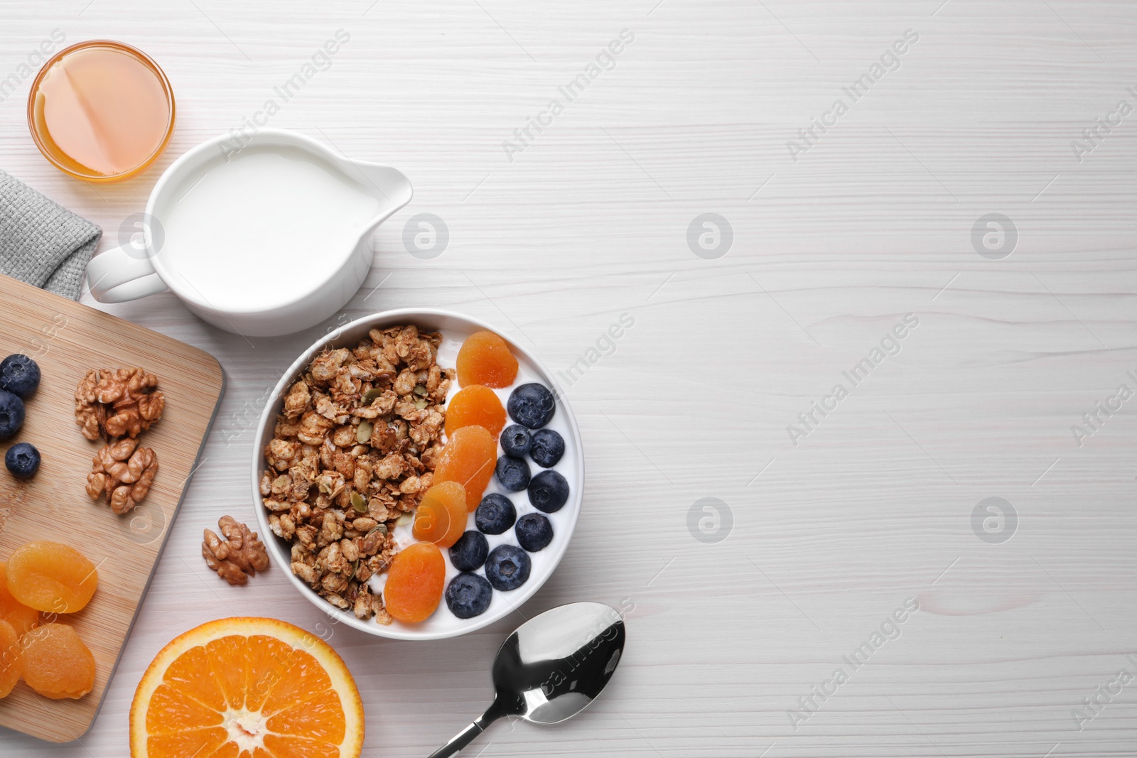 Photo of Delicious granola with fruits on white wooden table, flat lay. Space for text