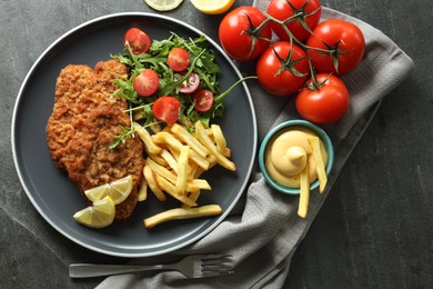 Photo of Tasty schnitzels served with potato fries, tomatoes and arugula on grey table, flat lay