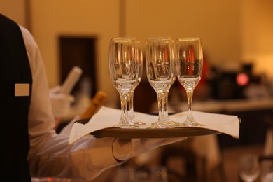 Photo of Butler holding tray with empty glasses in restaurant, closeup
