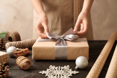 Photo of Woman wrapping Christmas gift at wooden table