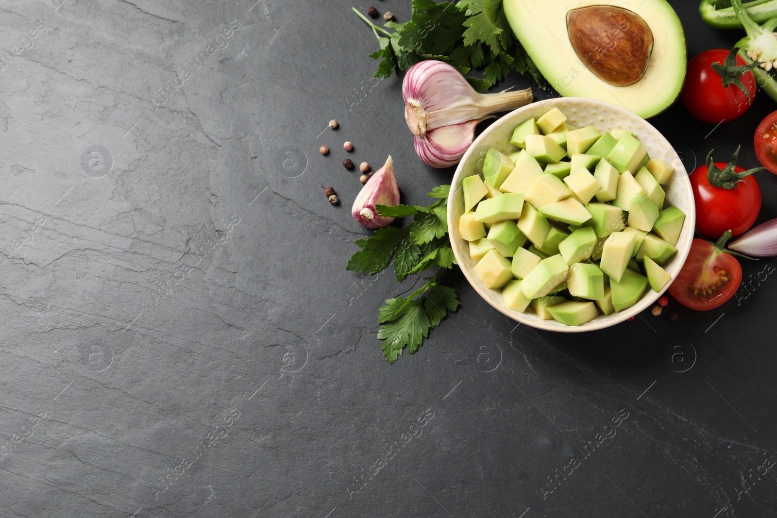 Photo of Fresh guacamole ingredients on black table, flat lay. Space for text