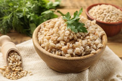 Photo of Delicious pearl barley with parsley in bowl on table, closeup