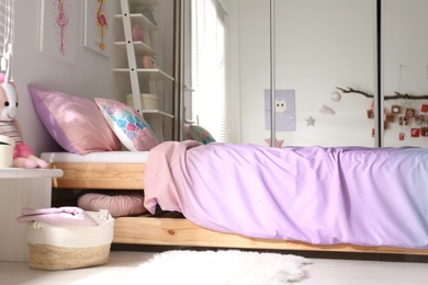 Bed with beautiful linens in children's room. Modern interior design