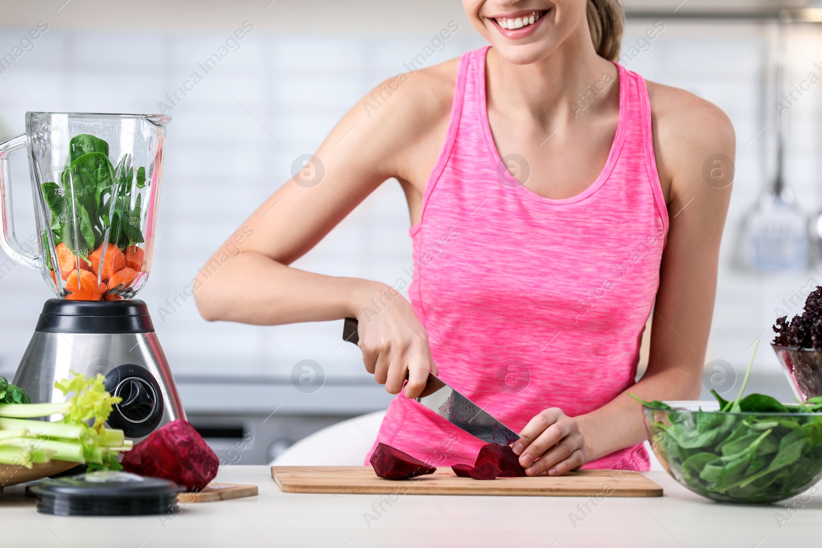 Photo of Young woman preparing tasty healthy smoothie at table in kitchen