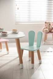 Photo of Small table and chair with bunny ears indoors. Children's room interior