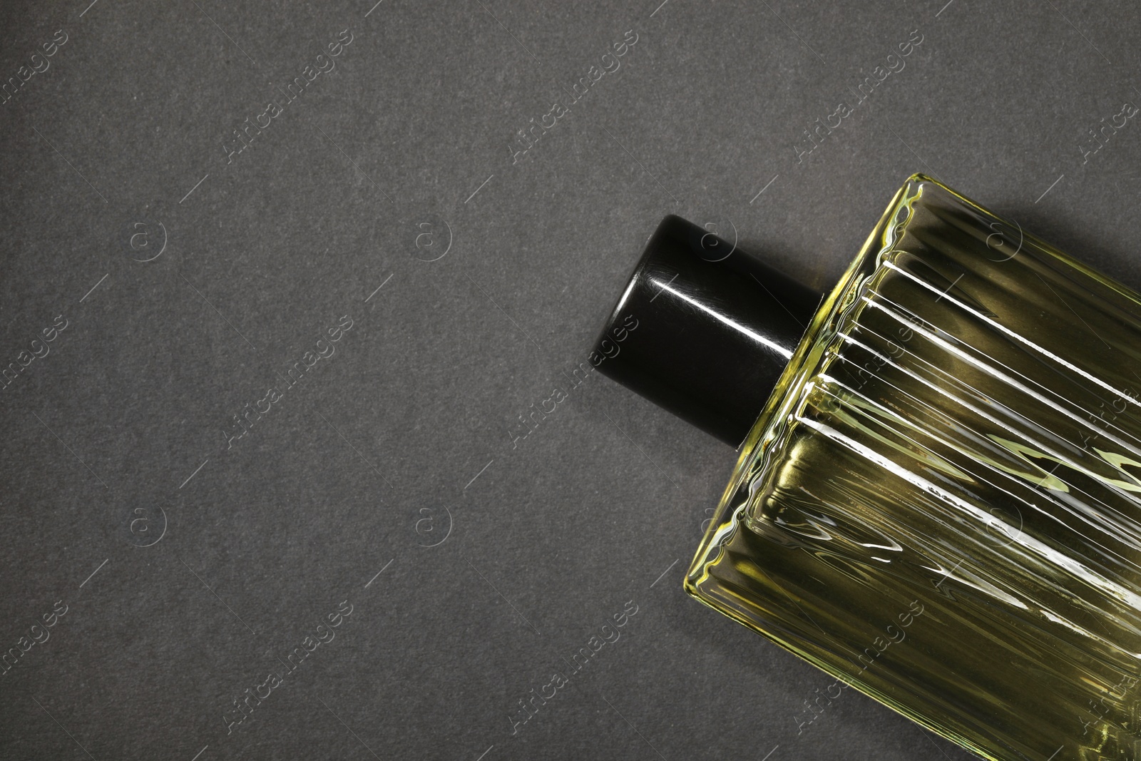 Photo of Luxury men`s perfume in bottle on black background, top view. Space for text