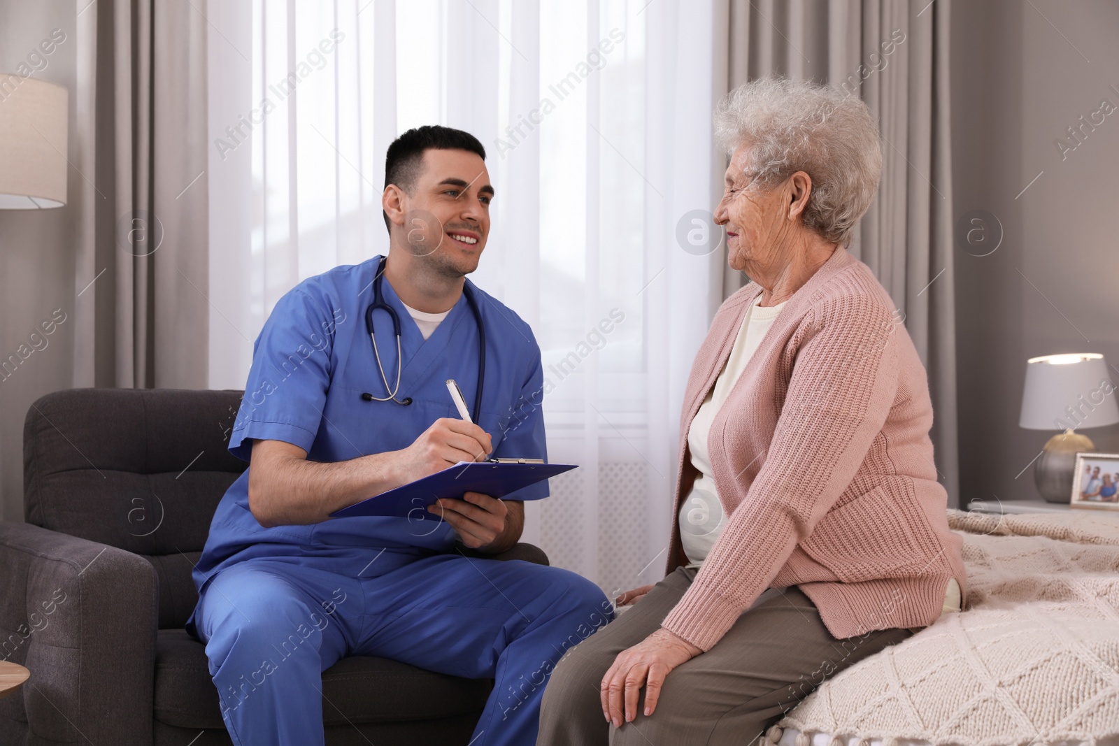 Photo of Young caregiver examining senior woman in bedroom. Home health care service