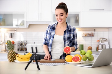 Photo of Young blogger with fruits recording video on kitchen