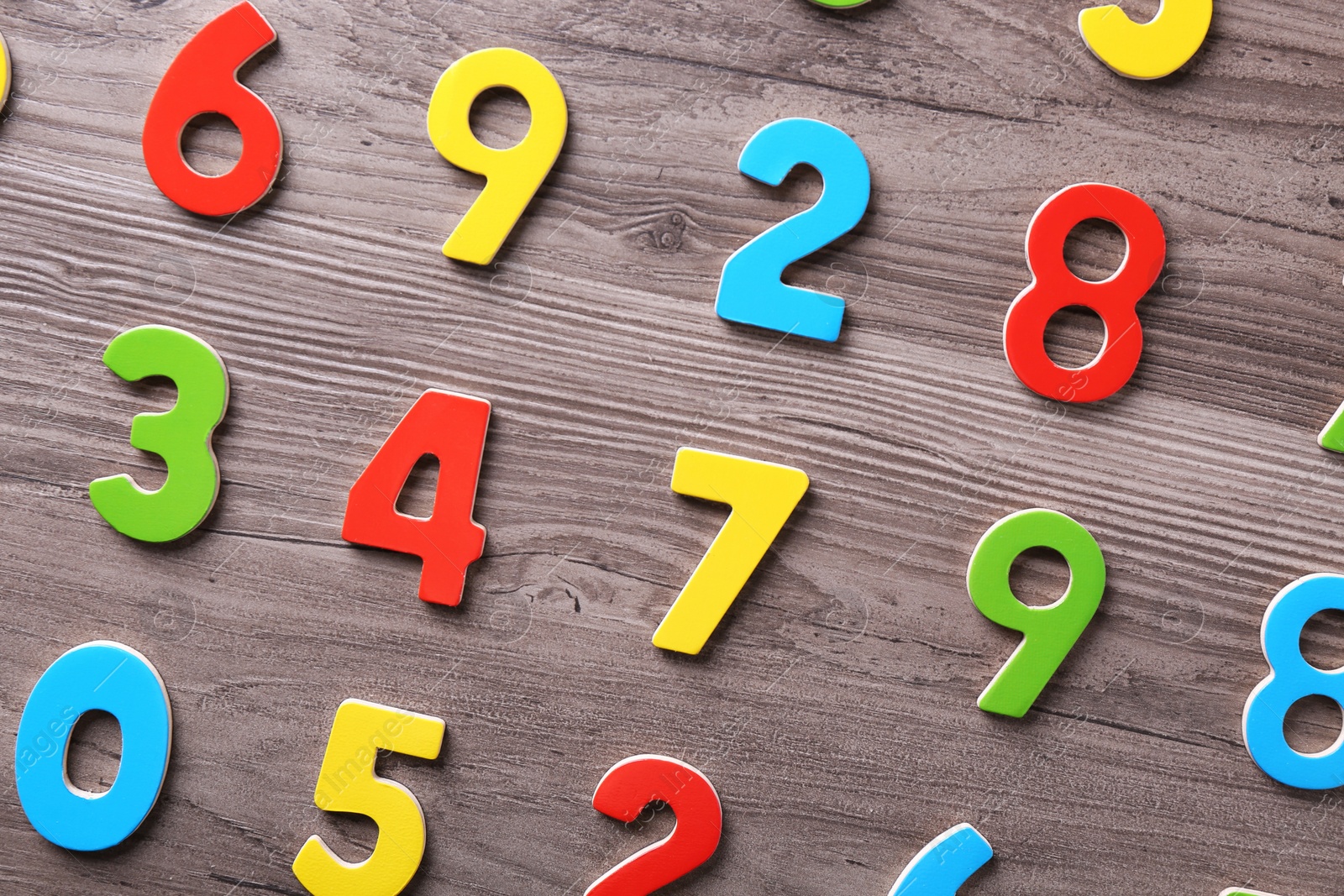 Photo of Colorful numbers on wooden school desk, flat lay