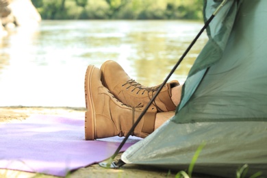 Young man resting in camping tent on riverbank, closeup. Space for text