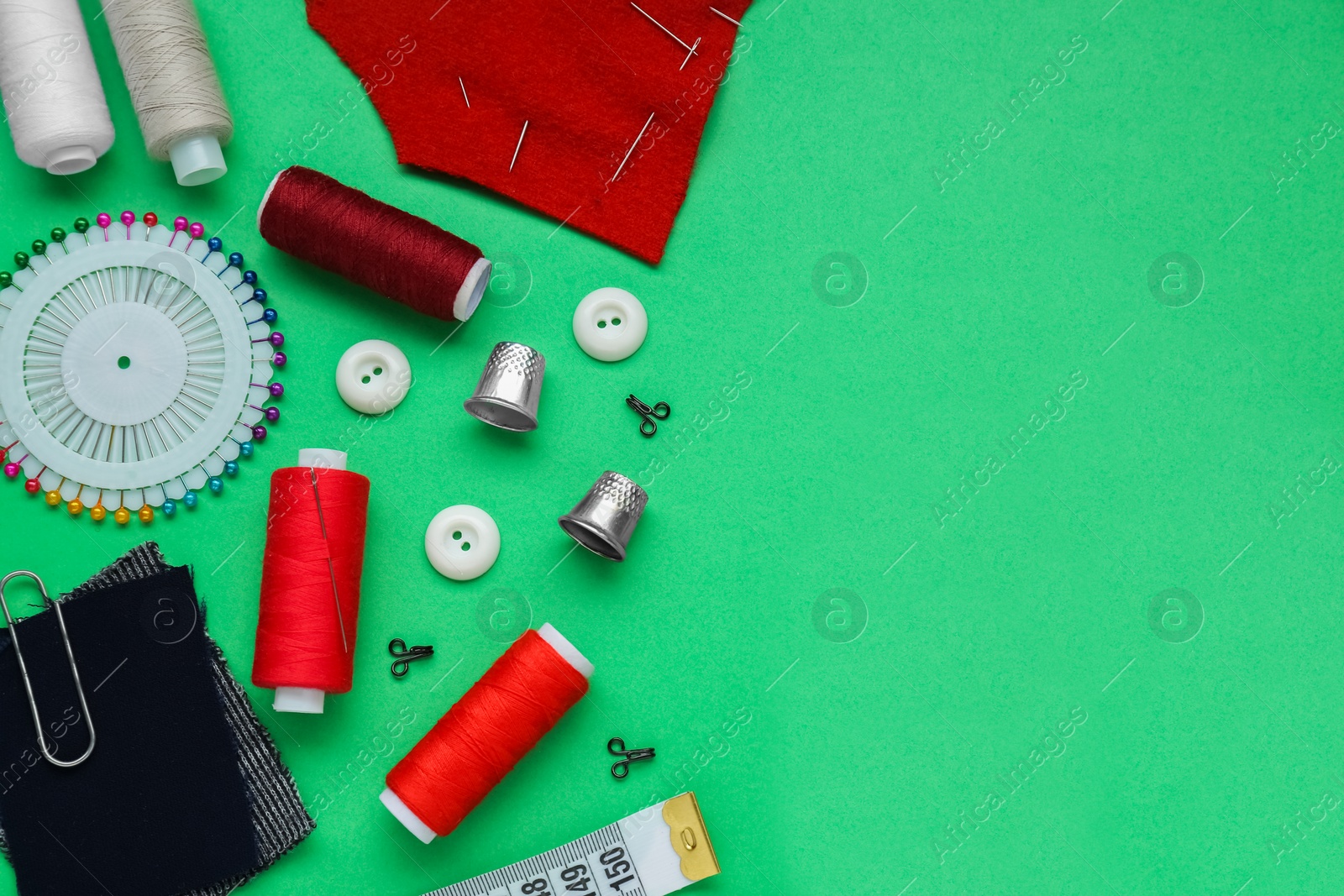Photo of Flat lay composition with thimbles and different sewing tools on green background. Space for text
