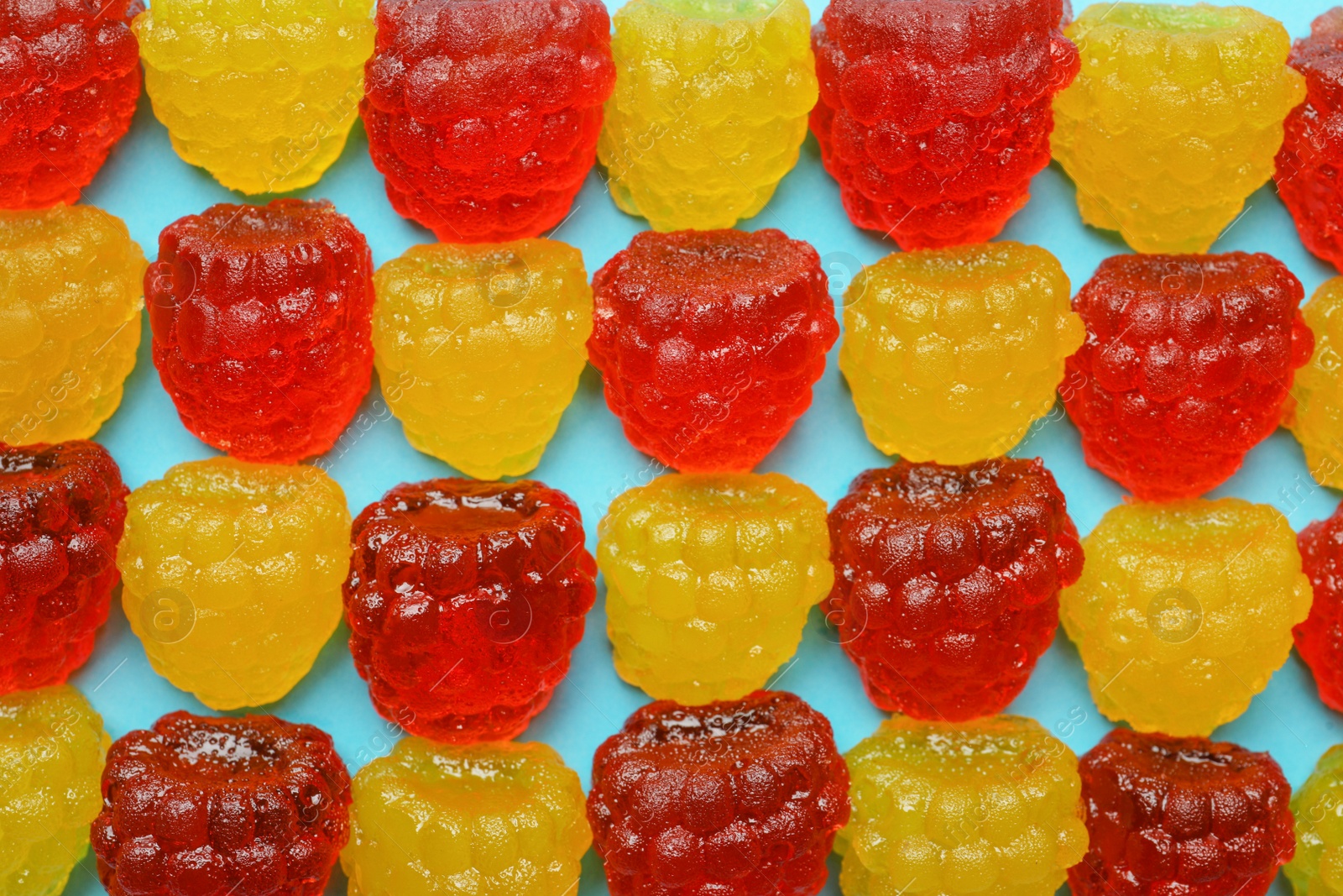 Photo of Delicious gummy raspberry candies on light blue background, flat lay