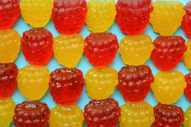 Delicious gummy raspberry candies on light blue background, flat lay