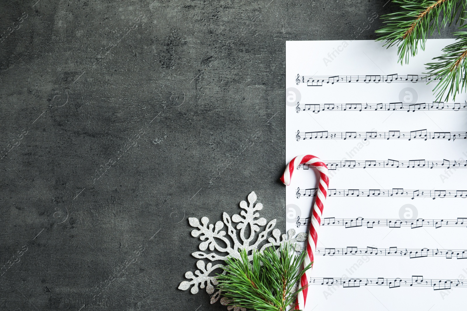 Photo of Flat lay composition with candy cane, fir branches and music sheet on table. Christmas songs concept