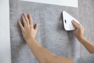 Man smoothing stylish gray wallpaper in room, closeup