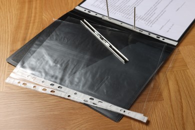 Photo of File folder with punched pockets on wooden table, closeup