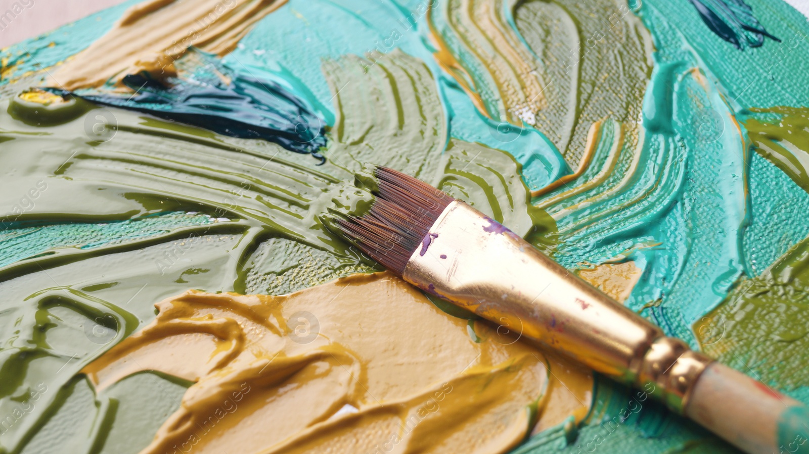 Photo of Brush on artist's palette with mixed paints, closeup