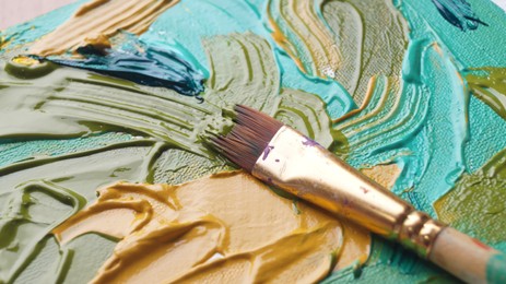 Brush on artist's palette with mixed paints, closeup