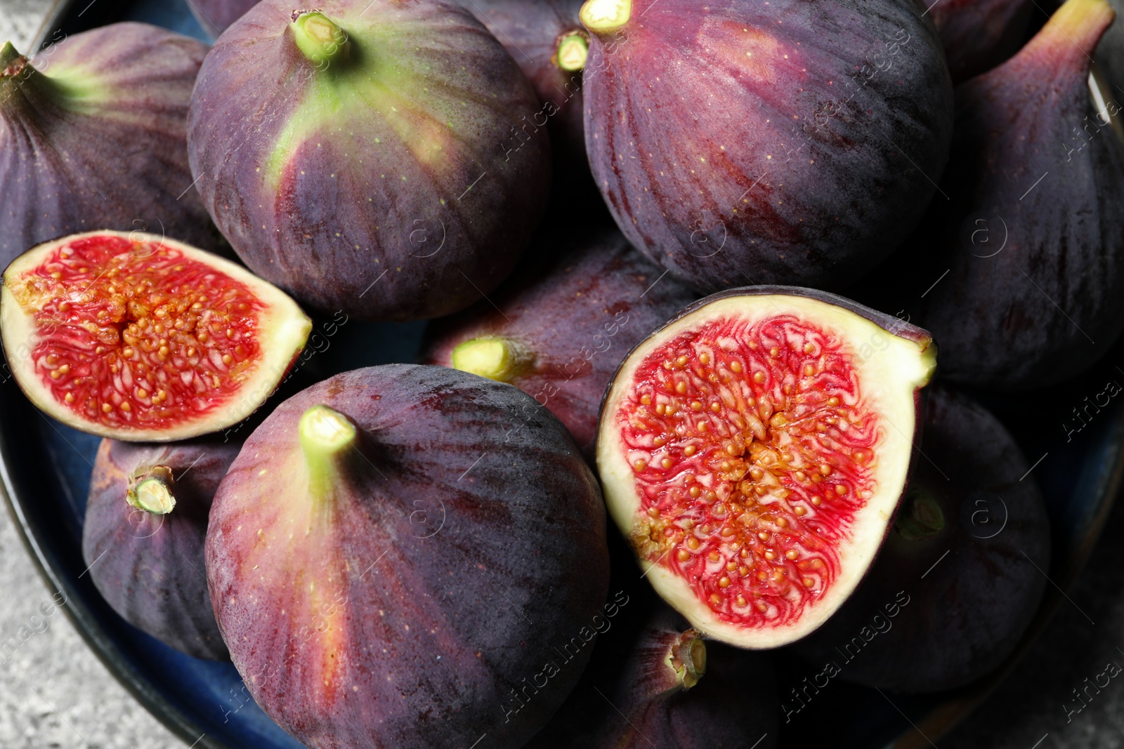 Photo of Whole and cut ripe figs on light grey table, top view