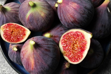 Whole and cut ripe figs on light grey table, top view