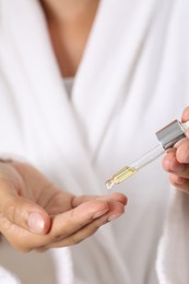 Photo of Woman applying cosmetic serum onto her finger, closeup