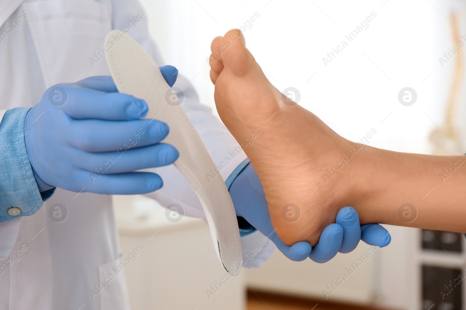 Photo of Male orthopedist fitting insole on patient's foot in clinic, closeup