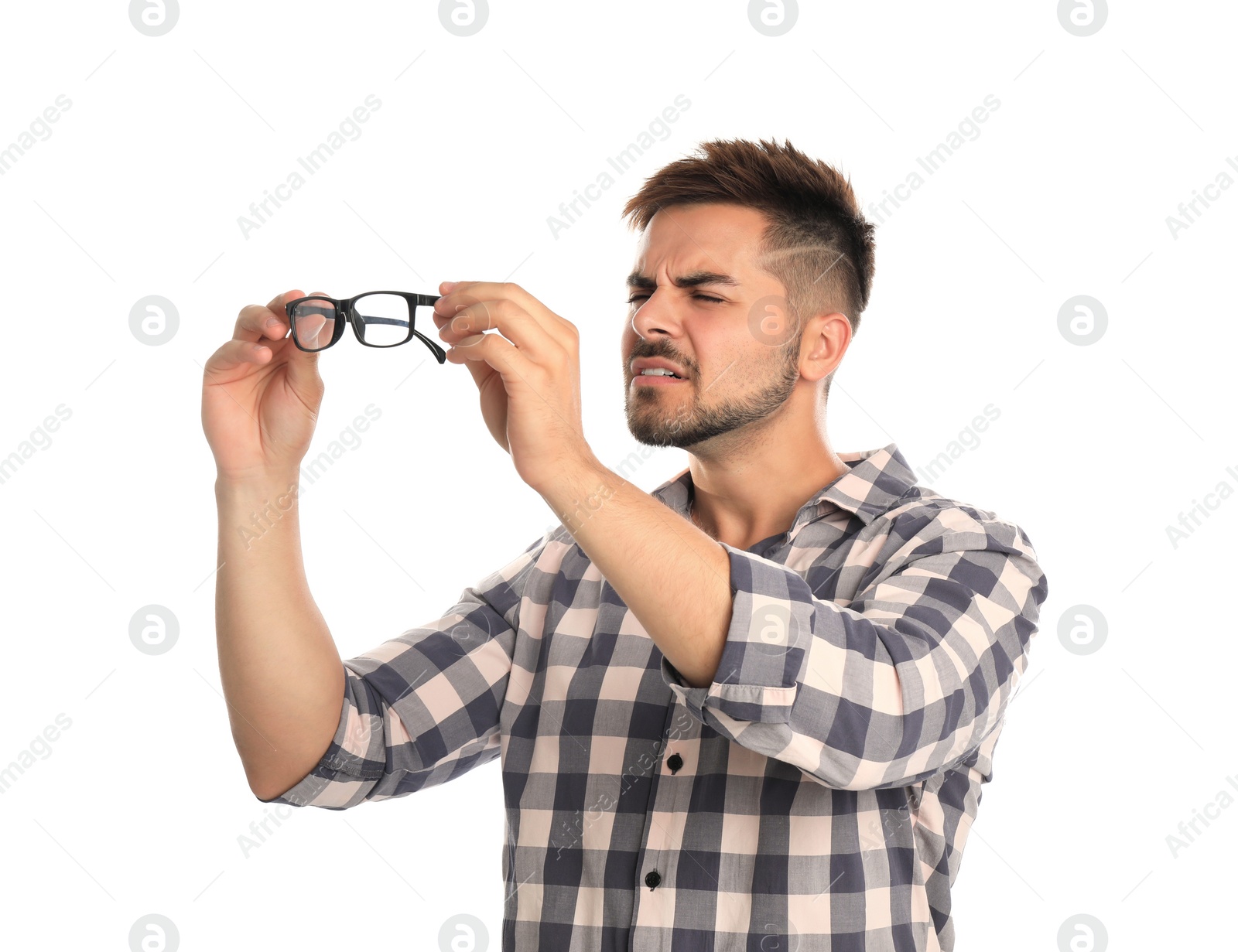 Photo of Young man with vision problems holding glasses on white background