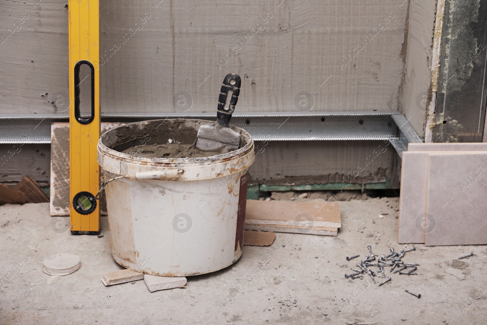 Photo of Adhesive mix, bubble level and ceramic tiles on floor indoors