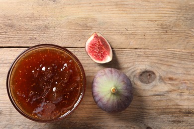 Photo of Bowl with tasty sweet jam and fresh figs on wooden table, flat lay. Space for text