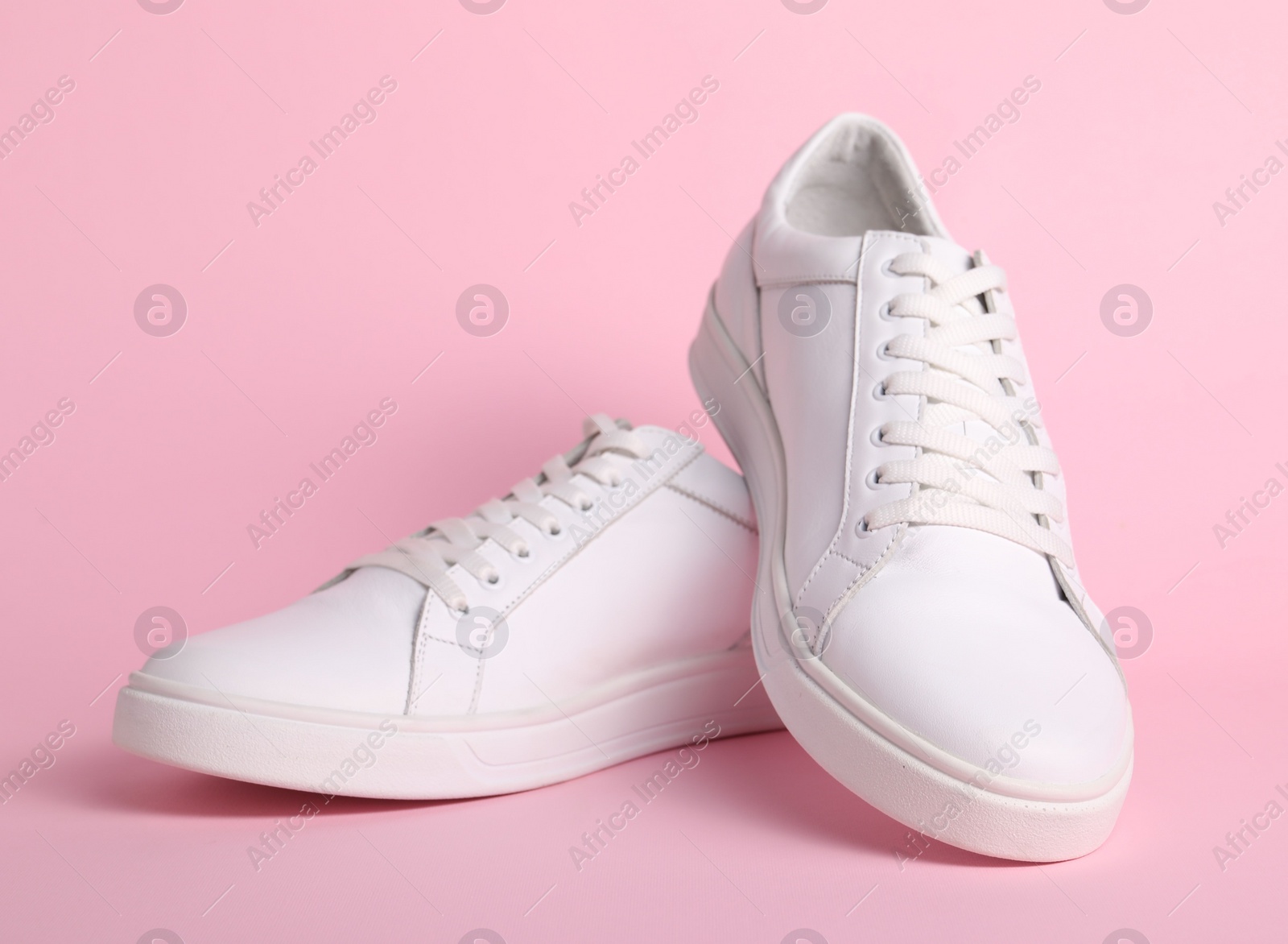 Photo of Pair of stylish white sneakers on pink background