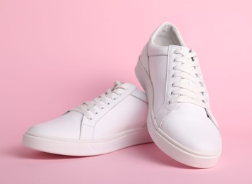 Photo of Pair of stylish white sneakers on pink background