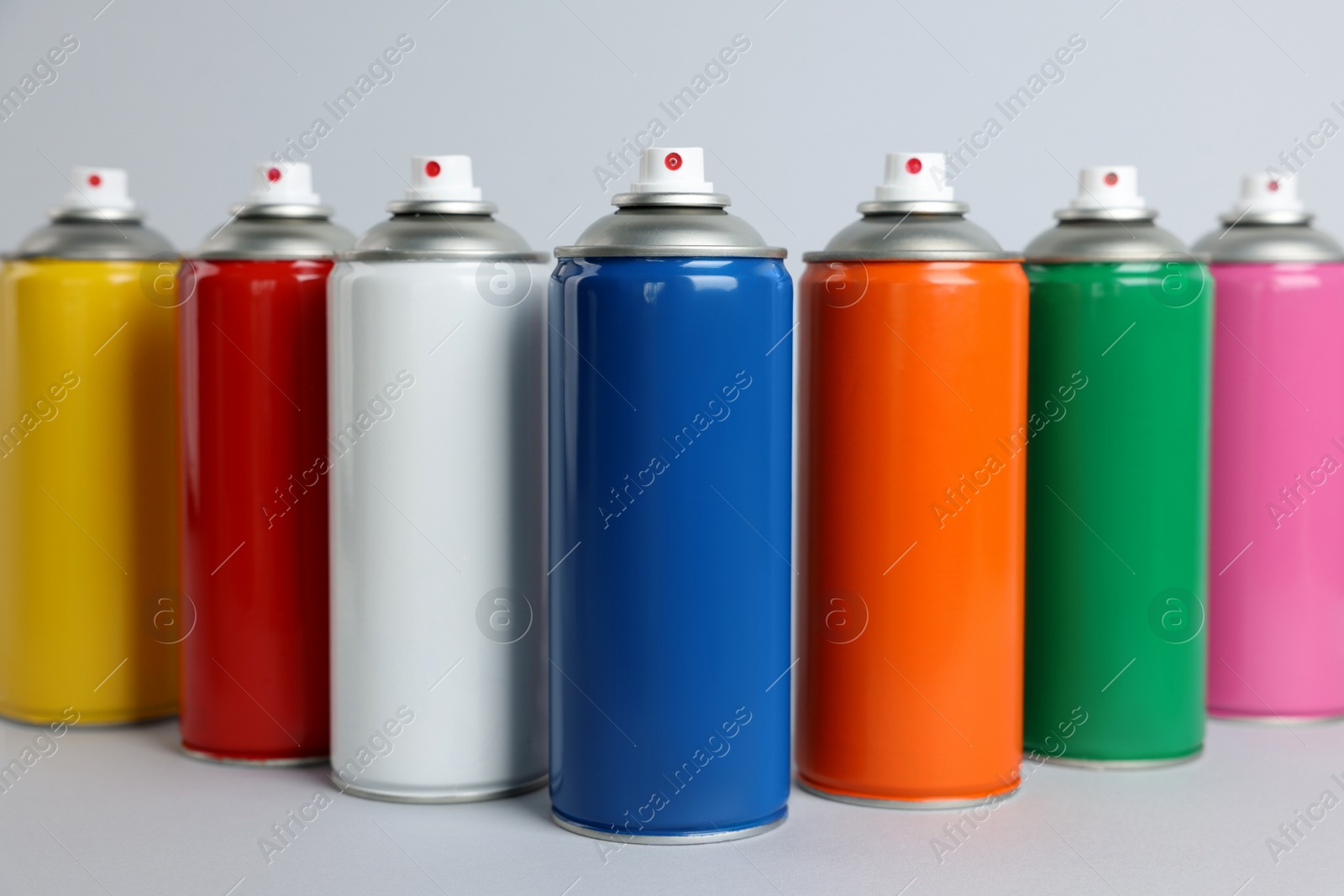 Photo of Colorful cans of spray paints on light grey background