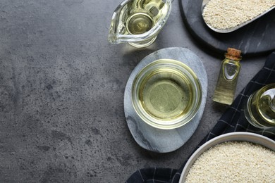 Photo of Sesame oil and seeds on dark grey table, flat lay. Space for text