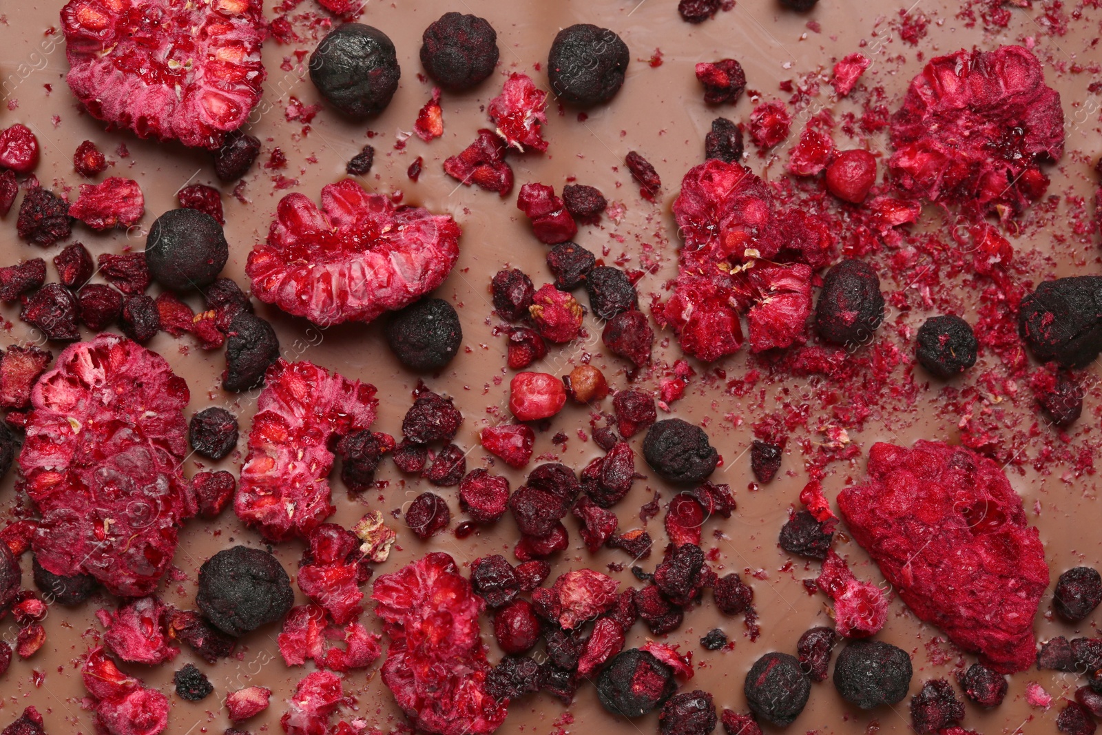 Photo of Chocolate bar with freeze dried berries as background, closeup