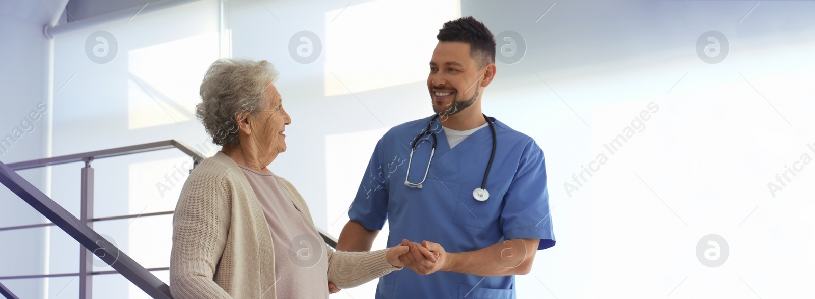 Image of Doctor helping senior patient in modern hospital. Banner design