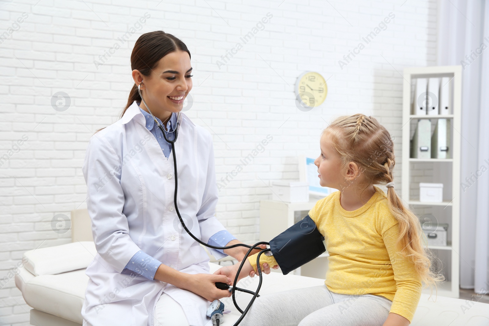 Photo of Little girl visiting doctor in hospital. Measuring blood pressure and checking pulse