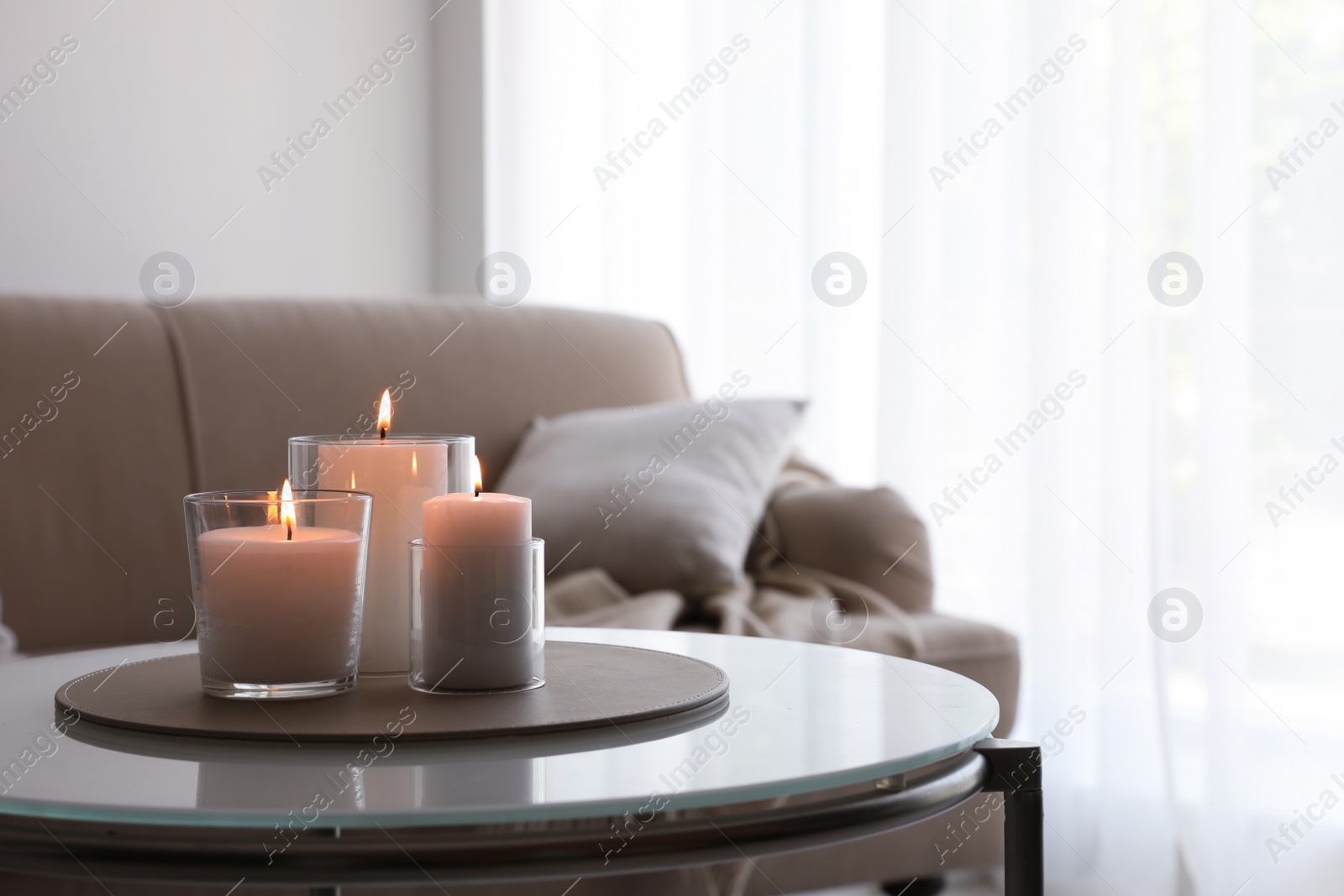 Photo of Burning candles in glass holders on table indoors. Space for text